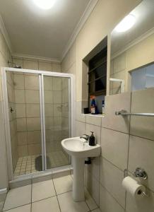 een badkamer met een douche, een wastafel en een glazen douchecabine bij Cleo's Corner in East London