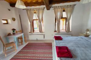 a bedroom with a bed and a table and windows at Verde de Viscri in Viscri