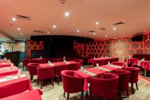 a restaurant with red tables and chairs in a room at City Palace Hotel in Dubai