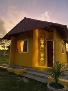 una pequeña casa amarilla con una puesta de sol en el fondo en Chalé Entre as Pedras en Serra de São Bento