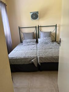a bed with two pillows and a clock on the wall at Pendleberry Holiday Resort - Unit 41 in Bela-Bela