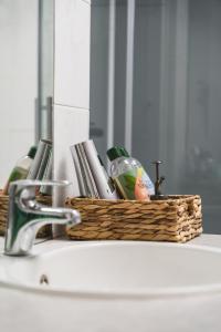een wastafel in de badkamer met een mand zeep en een spiegel bij Vakantiewoning & Fietslogies V E L O, Tussen Hasselt en Maastricht in Bilzen
