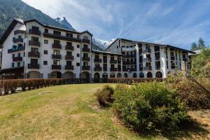 um grande edifício com um campo relvado à sua frente em Chamonix Sud - Bâtiment F 400 - Happy Rentals em Chamonix-Mont-Blanc