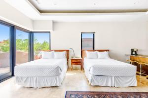 two beds in a white room with windows at Red Rock Escape with Suite in St. George