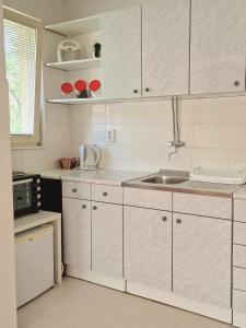 una cocina con armarios blancos y fregadero en Spago Apartment, en Konjic