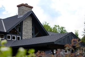 een huis met een zwart dak en een schoorsteen bij The Lodge at Lincoln Peak at Sugarbush in Warren