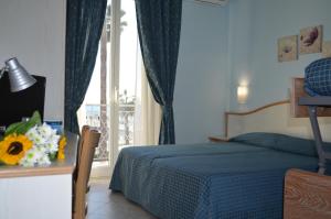 - une chambre avec un lit doté d'une couverture bleue et d'une fenêtre dans l'établissement Hotel Moresco, à Marina dʼAndora