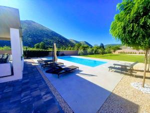 a villa with a swimming pool with mountains in the background at Villa Vita in Mostar
