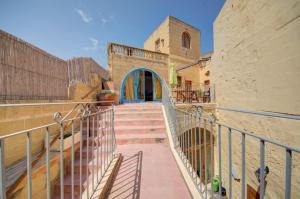 a staircase leading to a building with a blue door at Razzett Warda B&B in Għasri