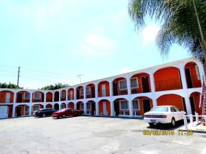 Un edificio naranja y blanco con autos estacionados en un estacionamiento. en Central Inn Motel, en Los Ángeles