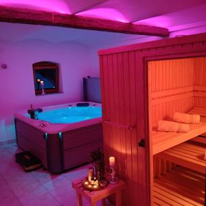 a bathroom with a tub and a sauna with purple lighting at Seoska vila Vallis Aurea in Kaptol
