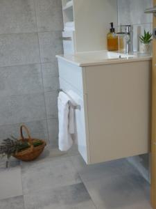 a white bathroom with a sink and a basket at Seoska vila Vallis Aurea in Kaptol