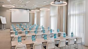 a conference room with tables and chairs and a screen at Hey Lou Hotel Monheim am Rhein in Monheim
