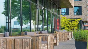 uma fila de mesas e cadeiras de madeira em frente a um edifício em Hey Lou Hotel Monheim am Rhein em Monheim