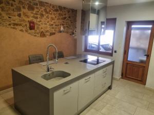 a kitchen with a sink and a stone wall at Hauzify I Casa Palamosina in Palamós