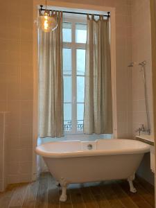 La salle de bains est pourvue d'une baignoire et d'une fenêtre. dans l'établissement les croix appartements, à Morlaix