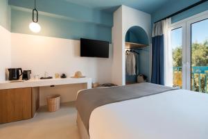 a bedroom with a bed and a desk and a tv at Play Paros in Kampos Paros