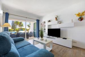 a living room with a blue couch and a tv at Apartamento Navegador in Sagres