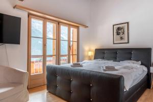 ein Schlafzimmer mit einem großen Bett und einem großen Fenster in der Unterkunft Apartment Alpin DG - GRIWA RENT AG in Grindelwald