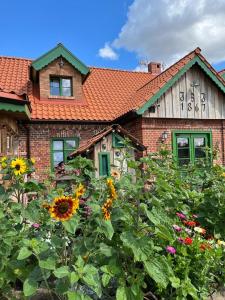 a house with a garden of flowers in front of it at Osada Między Drzewami in Braniewo