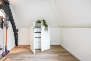 a white cabinet with a plant on it in a room at Beautiful Apartment With Loft in Delft