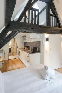 a bedroom with a white bed and a kitchen at Beautiful Apartment With Loft in Delft