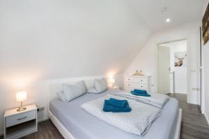 a white bedroom with a large white bed with blue pillows at Haus Friede in Kalkhorst