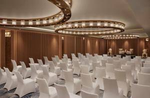 a conference room with white chairs and chandeliers at Taj Amer, Jaipur in Jaipur