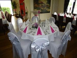 een lange tafel met witte stoelen en roze servetten bij Zum goldenen Hirsch am Paulaner in Höxter