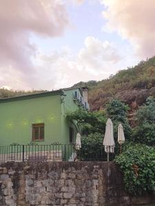 a green house with two umbrellas in front of it at Refugio La Presa in Chulilla