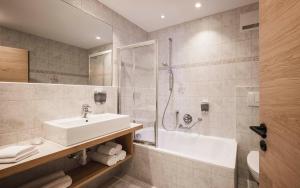 a bathroom with a sink and a shower and a tub at Hotel Alpenhof in Ultimo