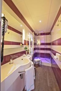 a bathroom with a tub and a sink at The Originals City - Hôtel Saint-Martial, Limoges Centre in Limoges