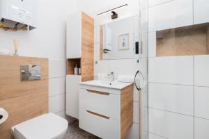 a white bathroom with a toilet and a sink at Old Town Apartment Garncarska by Renters in Gdańsk