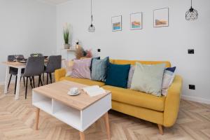 a living room with a yellow couch and a table at Old Town Apartment Garncarska by Renters in Gdańsk