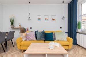 a living room with a yellow couch and a table at Old Town Apartment Garncarska by Renters in Gdańsk