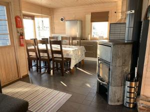 uma cozinha com uma mesa, cadeiras e um fogão em VILLA RIIHITONTTU MUURAME RIIHIVUORI em Muurame