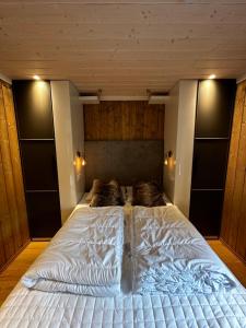 a large white bed in a bedroom with wooden walls at Nice apartment on Geilotunet, Close to city center in Geilo