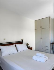 1 dormitorio con 1 cama blanca y 2 toallas en Pagonis Studios, en Lixouri