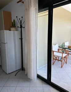 a kitchen with a sliding glass door with a table and a refrigerator at Pagonis Studios in Lixouri
