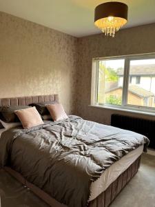 a bedroom with a bed with a window and a chandelier at Large 4 bedroom house, electric gated driveway. in Bidston