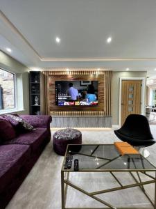 uma sala de estar com um sofá e uma televisão em Large 4 bedroom house, electric gated driveway. 