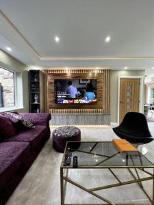 a living room with a couch and a tv at Large 4 bedroom house, electric gated driveway. in Bidston