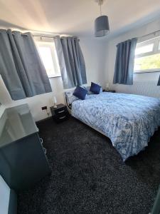 Schlafzimmer mit einem Bett mit blauer Bettwäsche und Fenstern in der Unterkunft 2-Bed House Bungalow in Bristol in Bristol