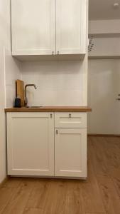 une cuisine avec des armoires blanches et un plancher en bois dans l'établissement Mini Wind Apartment, à Liepāja