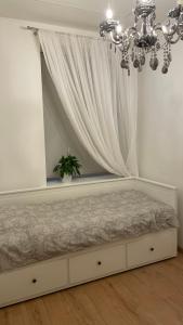 une chambre avec un lit avec un rideau et un lustre dans l'établissement Mini Wind Apartment, à Liepāja 5 autres photos