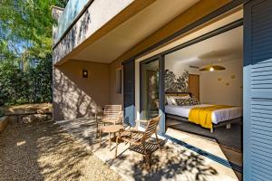 a bedroom and a balcony with a bed and chairs at Le Refuge - Gigaro Lodges in La Croix-Valmer