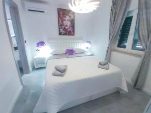 a bedroom with a white bed with two towels on it at Luxury two-bedroom apartment by the sea U KaLu in Postira