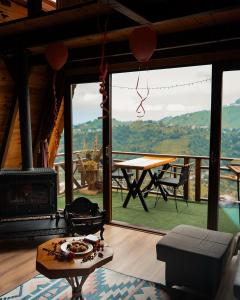 a living room with a fireplace and a table at Keyfi Teras Bungalov in Rize