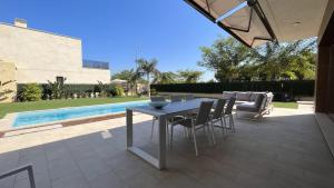 a patio with a table and chairs and a pool at Villa with private heated pool - Roda Golf & Beach Resort in San Javier