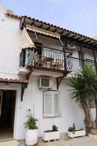 a white house with a balcony and a palm tree at Al Mar 2 in Skiathos